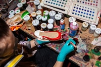 Lacey Hammond Harrington painting a ballet shoe with dye she has hand-mixed at the National Ballet of Canada in Toronto on February 15, 2024.