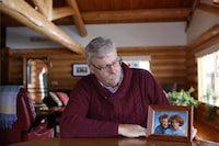 Gary Hertgers holds a framed photo from 2000 of twin sisters, Wilma "Willy" and Jenny "Jen" Hertgers, at his home in Lumby, B.C., on Nov. 18, 2022. Wilma, left, received medical assistance in dying in January 2022, while Jen died of cancer in 2008. (Aaron Hemens/The Globe and Mail)