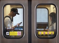 TTC passengers using their mobile phones while heading south on the Yonge subway line are photographed on Aug 21, 2023. (Fred Lum/The Globe and Mail)