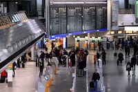 Passengers line up at a desk as cancelled flights are displayed on a board at the airport in Frankfurt am Main, western Germany, on January 17, 2024, as severe winter weather warnings prompted the cancellation of hundreds of flights. A Frankfurt airport spokeswoman said 570 of 1,047 flights had been axed from the schedule as Germany's business capital prepares for dramatic weather conditions. (Photo by Kirill KUDRYAVTSEV / AFP) (Photo by KIRILL KUDRYAVTSEV/AFP via Getty Images)