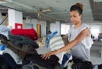 A coalition of Montreal community groups say they need more resources to help the growing number of asylum seekers arriving in the city. Volunteer Cynthia Nelson sorts through clothes donated to help new asylum seekers at a drop-off centre in Montreal, Sunday, Aug. 13, 2017. THE CANADIAN PRESS/Graham Hughes