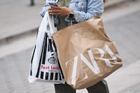 (FILES) A shopper uses an Apple iPhone as they carry Foot Locker and Zara shopping bags while walking down the Third Street Promenade in Santa Monica, California on March 20, 2023. A key indicator of US inflation cooled in June to the lowest annual rate in over two years, although this remains above the central bank's target, according to government data released on July 28, 2023. The Federal Reserve's preferred gauge of inflation, the personal consumption expenditures (PCE) price index, rose 3.0 percent last month from June 2022, down from a 3.8 percent jump in May, said the Commerce Department. (Photo by Patrick T. Fallon / AFP) (Photo by PATRICK T. FALLON/AFP via Getty Images)