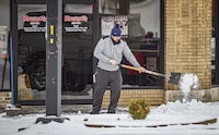 A man shovels snow from a sidewalk in front of Mugshots Grill & Bar, Thursday, Jan. 18, 2024, in downtown Florence, Ala. (Dan Busey/The TimesDaily via AP)