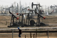 FILE - A worker walks near pumpjacks operating at the Kern River Oil Field in Bakersfield, Calif., Jan. 16, 2015. The oil and gas industry’s emissions are a main cause of climate change and in the past the industry undermined sound evidence that carbon greenhouse gases warm the atmosphere. (AP Photo/Jae C. Hong, File)