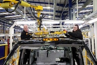 Workers fit a roof panel on the TX electric taxi production line inside the LEVC (London Electric Vehicle Company) factory in Coventry, Britain, January 18, 2023. REUTERS/Phil Noble/File Photo