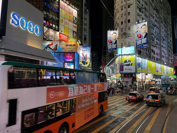 A bus with an election advert passes a busy shopping area in Hong Kong's Causeway Bay neighbourhood on Sunday, December 19, 2021.
