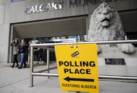 Pedestrians walk past an advance polling station sign outside Calgary City Hall in Calgary, Alta., Friday, April 12, 2019. THE CANADIAN PRESS/Jeff McIntosh