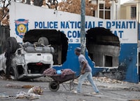 A man pushes a wheelbarrow past a destroyed police station in Port-au-Prince, Haiti’s capital city on April 19, 2024. Goran Tomasevic/The Globe and Mail