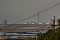 FILE - The Zaporizhzhia nuclear power plant, Europe's largest, is seen in the background of the shallow Kakhovka Reservoir after the dam collapse, in Energodar, Russian-occupied Ukraine, Tuesday, June 27, 2023. Officials at the Russian-controlled Zaporizhzhia Nuclear Power Plant said that the site was attacked Sunday April 7, 2024, by Ukrainian military drones, including a strike on the dome of the plant’s sixth power unit. (AP Photo/Libkos, File)
