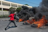 A protester burns tires during a demonstration following the resignation of its Prime Minister Ariel Henry, in Port-au-Prince, Haiti, on March 12, 2024. A political transition deal in Haiti marks a key step forward for the violence-ravaged country but far more needs to be done, with some experts warning the situation could deteriorate further. (Photo by Clarens SIFFROY / AFP) (Photo by CLARENS SIFFROY/AFP via Getty Images)