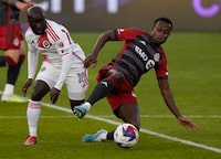 Toronto FC midfielder Richie Laryea (22) goes to ground to control the ball as New England Revolution midfielder Ema Boateng (18) defends during first half MLS soccer action in Toronto on Saturday May 6, 2023. Toronto FC has reacquired Laryea from England's Nottingham Forest. THE CANADIAN PRESS/Frank Gunn