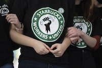 FILE - Starbucks employees and supporters link arms during a union election watch party Dec. 9, 2021, in Buffalo, N.Y. Starbucks says it’s committed to bargaining with unionized workers and reaching labor agreements next year. The move Friday is major reversal for the coffee chain after two years fighting the unionization of its U.S. stores. (AP Photo/Joshua Bessex, File)