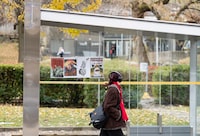 A student walks past a bus shelter where pro-Palestinian posters were taped outside the University of Montreal metro station in Montreal, Tuesday, Nov., 14, 2023.  THE CANADIAN PRESS/Christinne Muschi