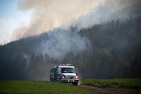 The federal government is doubling its investment to train urban firefighters to battle wildfires, which pose a growing threat to Canada's cities and towns. Firefighters drive across a farm while monitoring a controlled burn near a wildfire northwest of Vernon, B.C., Wednesday, Aug. 25, 2021. THE CANADIAN PRESS/Darryl Dyck