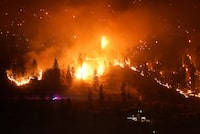 The McDougall Creek wildfire burns on the mountainside above a lakefront home, in West Kelowna, B.C., on Friday, Aug. 18, 2023. THE CANADIAN PRESS/Darryl Dyck