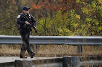 A police officer walks along a rural road during a manhunt for the suspect of Wednesday's mass shootings, Thursday, Oct. 26, 2023, in Lisbon, Maine. The shootings took place at a restaurant and bowling alley in nearby Lewiston, Maine. THE CANADIAN PRESS/AP-Robert F. Bukaty