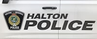 The prospective adoptive parents of a 12-year-old boy who was found dead in a Burlington home more than a year ago are now facing first-degree murder charges. A Halton Regional Police logo is shown on the side of a police vehicle in Oakville, Ont., Wednesday, Jan.18, 2023. THE CANADIAN PRESS/Richard Buchan