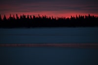 Across the Albany River from the Marten Falls First Nation, the sky glows red as the sun sets in the northern Ontario community on Dec. 13, 2023. Marten Falls FN sits at the confluence of the Albany and Ogoki Rivers. (Fred Lum/The Globe and Mail)