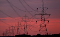 FILE PHOTO: The sun rises behind electricity pylons near Chester, northern England October 24, 2011.  REUTERS/Phil Noble/File Photo