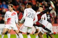 Toronto FC's Prince Osei Owusu (99) tumbles as he scores as New England Revolution's Mark-Anthony Kaye (28) looks on during second half MLS soccer action in Toronto on Saturday, April 20, 2024. THE CANADIAN PRESS/Frank Gunn