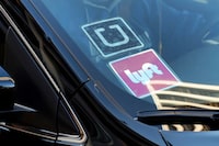FILE - In this Jan. 12, 2016, file photo, a ride share car displays Lyft and Uber stickers on its front windshield in downtown Los Angeles.  Thousands of U.S. ride-hailing workers plan to park their cars and picket at major U.S. airports Wednesday, Feb. 14, 2024, in what organizers say is their largest strike yet in a drive for better pay and benefits. (AP Photo/Richard Vogel, File)