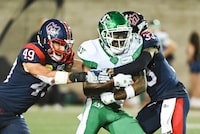 Saskatchewan Roughriders' Samuel Emilus, centre, is tackled by Montreal Alouettes' Frederic Chagnon (49) and Kordell Rodgers (33) during second half CFL football action in Montreal, Friday, August 11, 2023. THE CANADIAN PRESS/Graham Hughes