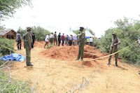 Police officers stand near a cordon at the scene where police are exhuming bodies of victims of Christian cult that has led to death of dozens of followers, at a forest in Shakahola area, outskirts of Malindi town, Kenyan Coast Tuesday, April 25, 2023. Kenya's president William Ruto said Monday that the starvation deaths of dozens of followers of pastor Paul Makenzi, who was arrested on suspicion of telling his followers to fast to death in order to meet Jesus, is akin to terrorism (AP Photo)