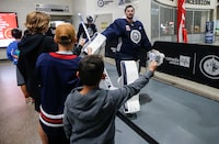 Winnipeg Jets goaltender Connor Hellebuyck (37) high-fives hockey fans as the team changes rinks during day two of their NHL training camp in Winnipeg, Friday, September 22, 2023. Connor Hellebuyck and Mark Scheifele hope their new contracts show their teammates and fans how much they believe in the Winnipeg Jets. THE CANADIAN PRESS/John Woods
