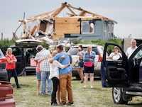 People embrace after a tornado damaged homes near Carstairs, Alta., Saturday, July 1, 2023. No injuries were reported. THE CANADIAN PRESS/Jeff McIntosh