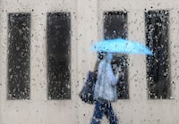 An early spring storm is bringing high winds and heavy rain to parts of Ontario as Environment Canada warns of significant snowfall in other parts of the province. A pedestrian walks on a rainy day in Toronto on Friday, June 18, 2021. THE CANADIAN PRESS/Nathan Denette