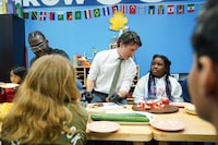 Prime Minister Justin Trudeau talks to ten year old Chakai as cuts fruit next to chef Jason Simpson at photo opportunity as they prepare food for a lunch program at the Boys and Girls Club East Scarborough, in Toronto, before an announcement to launch a National School Food Program, Monday, April 1, 2024. The Government is to commit $1 billion over five years with the hope that the program will deliver meals to an additional 400,000 children per year. THE CANADIAN PRESS/Chris Young