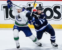Winnipeg Jets' Dylan DeMelo (2) defends against Vancouver Canucks' Pius Suter (24) during first period NHL action in Winnipeg on Thursday, April 18, 2024. THE CANADIAN PRESS/John Woods