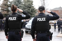 Barrie Police along with other emergency services salute as the hearse carrying OPP Const. Grzegorz "Greg" Pierzchala arrives to Adams Funeral Home in Barrie, Ont., Friday, Dec. 30, 2022. THE CANADIAN PRESS/Christopher Drost