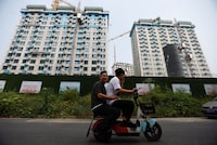 FILE PHOTO: People ride on a scooter past residential buildings under construction in Beijing, China September 6, 2023. REUTERS/Tingshu Wang