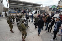 Israeli soldiers prevent Palestinian residents from approaching a demonstration by Jewish settlers in the West Bank town of Hawara, Sunday, March 26, 2023. The settlers called for a crackdown on Palestinians after a series of Palestinian shooting attacks in the area. (AP Photo/Majdi Mohammed)