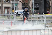 A police officer uses a fire extinguisher as emergency personnel respond to a report of a person covered in flames, outside the courthouse where former U.S. President Donald Trump's criminal hush money trial is underway, in New York, U.S., April 19, 2024.  REUTERS/Brendan McDermid