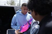 PSG's Kylian Mbappe stops to sign autographs for fans as he leaves the Paris Saint-Germain training complex, Friday, July 28, 2023 in Poissy, outside Paris. Speculation is mounting as to where Mbappé will play his first game of the season. (AP Photo/Lewis Joly)
