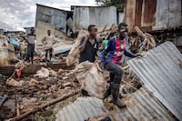 Boys carry some of their belongings after visiting their house that were destroyed by floods following torrential rains at the Mathare informal settlement in Nairobi, on April 25, 2024. Torrential rains triggered floods and caused chaos across Kenya, blocking roads and bridges and engulfing homes in slum districts. The death toll from flash floods in Kenya's capital Nairobi has risen to 13 on April 25, 2024, police said. Kenyans have been warned to stay on alert, with the forecast for more heavy rains across the country in the coming days. (Photo by LUIS TATO / AFP) (Photo by LUIS TATO/AFP via Getty Images)