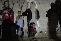 Family of Mahmoud Al-Said, who was accused of being an ISIS operative, stands next to a wall during a night raid in a village in Deir ez-Zor region, April 15, 2023.

