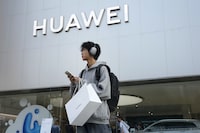 FILE - A customer carries his purchased Huawei product outside a Huawei store after he attended the Huawei new product launch conference in Beijing, on Sept. 25, 2023. Chinese telecoms gear company Huawei Technologies has reported its profit more than doubled last year as its cloud and digital businesses thrived in spite of U.S. sanctions. (AP Photo/Andy Wong, File)