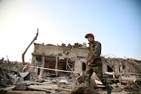 A soldier walks past a destroyed house in a residential area that was hit by rocket fire overnight by Armenian forces, early Saturday, Oct. 17, 2020, in Ganja, Azerbaijan's second largest city, near the border with Armenia. Azerbaijan has accused Armenia of striking its second-largest city with a ballistic missile that killed at least 13 civilians and wounded 50 others in a new escalation of their conflict over Nagorno-Karabakh. (AP Photo/Aziz Karimov)