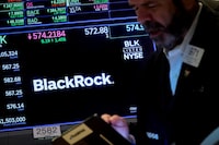A trader works as a screen displays the trading information for BlackRock on the floor of the New York Stock Exchange (NYSE) on Oct. 14, 2022.