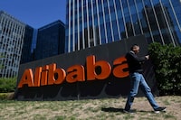 A man walks past an Alibaba sign outside the company's office in Beijing on April 13, 2021.