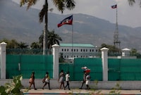 People walk past the National Palace in Port-au-Prince, Haiti, Monday, March 25, 2024. (AP Photo/Odelyn Joseph)