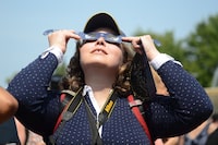 Canada's largest school board is voting Wednesday on whether it should revise its school calendar so students can stay home on the day a rare solar eclipse will partially and, for a fleeting few minutes in some areas, totally dim daylight. Observers watch a solar eclipse at the Canadian National Exhibition in Toronto on Monday, August 21, 2017. THE CANADIAN PRESS/Jon Blacker