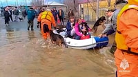 In this image taken from a video released by the Russian Emergency Ministry Press Service on Saturday, April 6, 2024, emergency workers evacuate local residents with their pets after a part of a dam burst causing flooding, in Orsk, Russia. Floods hit a city in the Ural Mountains areas after a river dam burst there, prompting evacuations of hundreds of people, local authorities said. The dam breach in Orsk, a city less than 20 kilometers north of Russia's border with Kazakhstan, occurred on Friday night, according to Orsk mayor Vasily Kozupitsa. (Russian Emergency Ministry Press Service via AP)