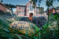 A hand painted stone lies in the grass at a memorial outside the former Kamloops Indian Residential School in Kamloops, B.C., Thursday, June 1, 2023. The remains of 215 children were discovered buried near the former Kamloops Indian Residential School in 2021. THE CANADIAN PRESS/Jeff McIntosh