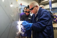 Ontario Premier Doug Ford, right, gets help from grade 11 student Shannon Williams, 16, as they practise welding at St. Mary Catholic Secondary School in Pickering, Ont., on Wednesday, March 8, 2023.  Ontario high school students will soon be able to spend most of their time in Grade 11 and 12 in an apprenticeship, if they choose to participate in a new skilled trades program.THE CANADIAN PRESS/Nathan Denette