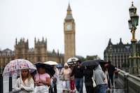 A pedestrian with a UK themed umbrella walks across Westminster Bridge, across the River Thames, with the Elizabeth Tower, commonly called Big Ben in the back ground, in central London, on July 31, 2023 on a gloomy and rainy summer day. (Photo by HENRY NICHOLLS / AFP) (Photo by HENRY NICHOLLS/AFP via Getty Images)