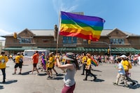 A participant waves a rainbow flag as the crowd marches during Pride Parade in Saskatoon, Sask., on Saturday, June 18, 2022. A community organization representing LGBTQ+ people in Regina has filed legal action against the Saskatchewan government over a pronoun policy affecting children at school. THE CANADIAN PRESS/Heywood Yu